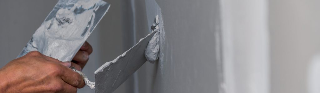 old manual worker with wall plastering tools renovating house. Plasterer renovating indoor walls and ceilings with float and plaster.