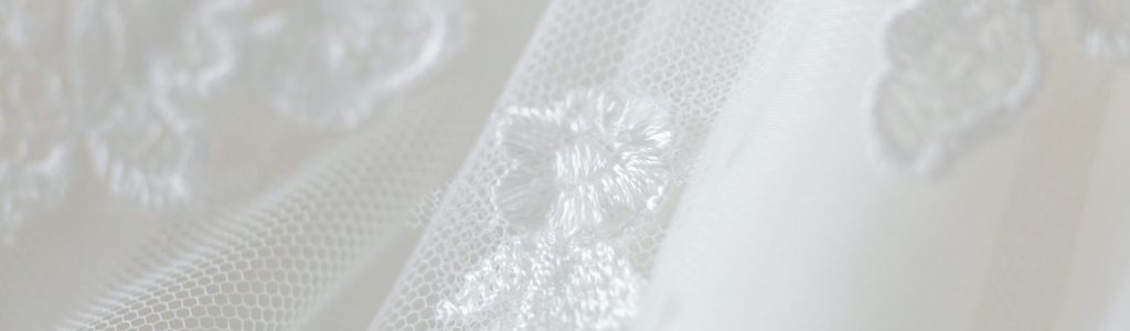 Delicate wedding dress detail close up of lace stitching